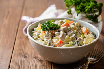 Traditional Russian salad Olivier in bowl on wooden table. Selective focus.