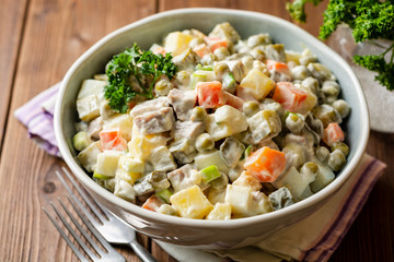 Traditional Russian salad Olivier in bowl on wooden table. Selective focus.