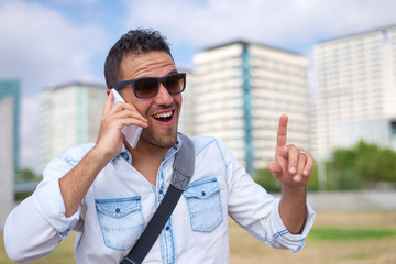 young man wearing sunglasses while using mobile phone in the street.