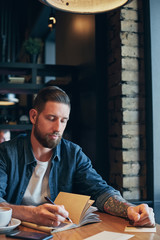 Man hand with pen writing on notebook on a wooden table.