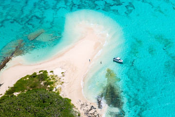 Tourists, divers, snorkelers, jet boat, an idyllic empty sandy beach of remote island, azure turquoise blue lagoon, West Coast barrier reef, aerial view. New Caledonia, Melanesia, South Pacific Ocean