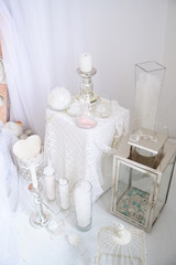Romantic white decor with candlesticks and candles, beautiful details in a bright room. Wedding decor or Valentine's day