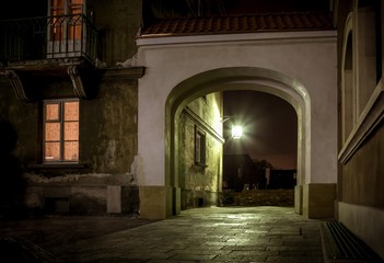 latarnia rozświetla mrok w bramie nocą