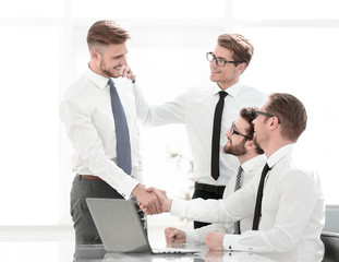 friendly handshake colleagues near the desktop