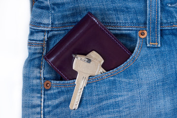 Wallet and keys to the house on a keychain are lying in a side pocket of blue jeans.
