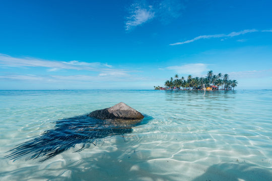 Little island with palms and building between water