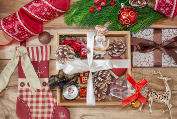 Christmas gifts in a wooden box on a wooden background. Christmas tree branches, decorations, cones, angel and gifts.