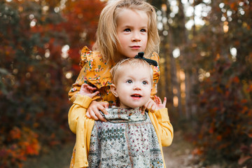 Young children walk in the autumn forest in retro dresses.
