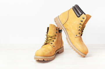 Yellow men's work boots from natural nubuck leather on wooden white background. Trendy casual...