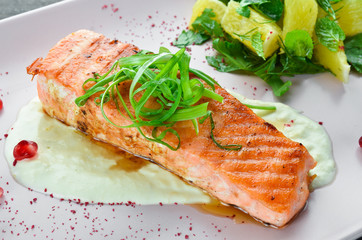 Baked salmon fillet with vegetables on a plate. On a wooden background. Top view. Free space for your text.