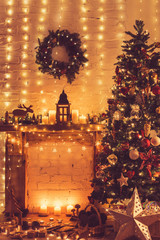 Beautiful warm interior, decorated fireplace with solid wood mantelpiece, lit up Christmas tree with baubles and ornaments, stars and lights, candles. handmade wreath, toned, selective focus