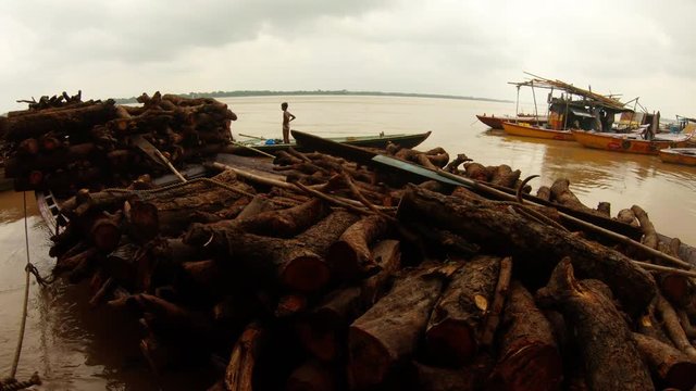 Boats with piles of firewood indian boy stands in small bark cogs on pier river Ganges high water Manikarnika burning ghat