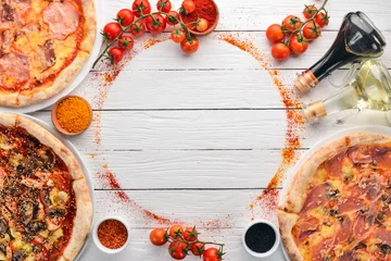 Fotobehang Een set van Italiaanse pizza. Italiaanse keuken. Op een witte houten achtergrond. Gratis exemplaar ruimte. Bovenaanzicht. © Yaruniv-Studio