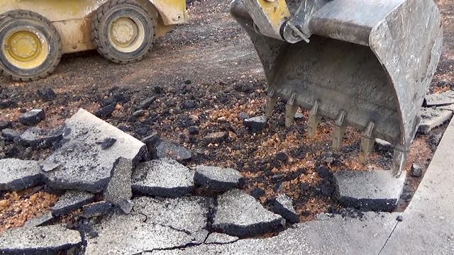 excavator removes the bucket with the pavement layer with a bituminous conglomerate