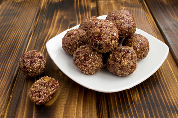 Energy balls with dried cranberry in the white plate on the brown wooden background