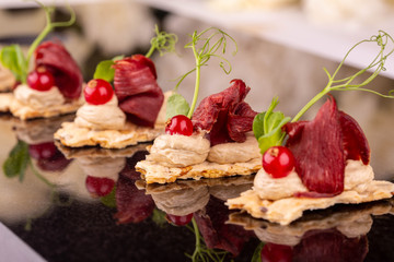 Dried venison on a rye toast with red currant and greens