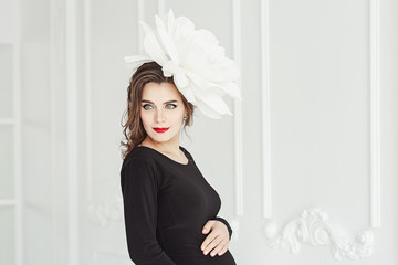 Portrait of young pregnant woman with white big flower in her had.