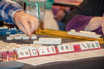 Hand of player reaching for tile in a game of Mahjong - selective focus