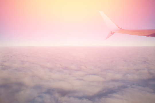 Wing of airplane with flare sun, high above clouds.