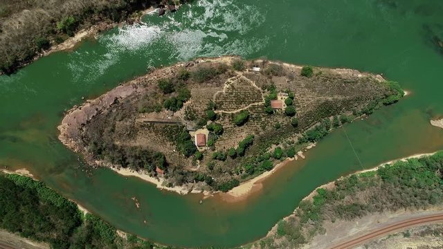 Drone zoom in over island in the middle of the river Doce. Trees and small houses below. Following, tilt up to the river landscape. On the horizon mountains and cloudy sky. Atlantic Forest Biome. 