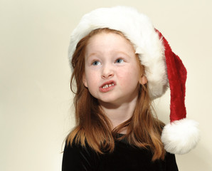 Child wearing Christmas hat is displeased