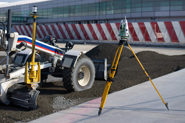 Surveyor equipment (theodolite) on construction site of the airport, building or road with...