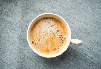 A cup of fresh coffee with beautiful foam on grey background. Flat lay style.