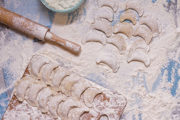 Dumplings with rolling pin on table sprinkled with flour