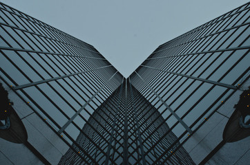 A abstract view of the corner glass building in the overcast sky in the downtown area. 