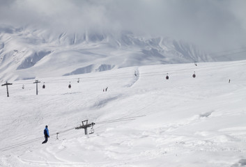 Fototapeta na wymiar Snowboarder descend on snowy ski slope and high mountains in dark cloud