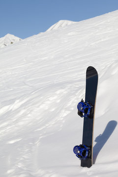 Snowboard in snowdrift after snowfall and mountains in background