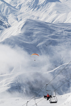 Chair-lift and paraplane in fog on ski resort