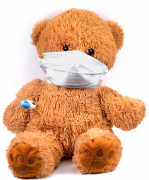 toy bear in a medical mask and a thermometer on a white background