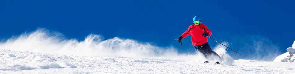 Fotobehang Wintersport Man skiën op de geprepareerde helling met verse nieuwe poedersneeuw
