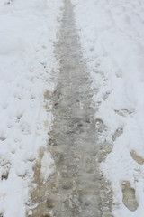 Snow landscape. Wet path trodden by pedestrians through the snow