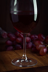 Spanish wine glass with bunch of grapes on dark wood stage
