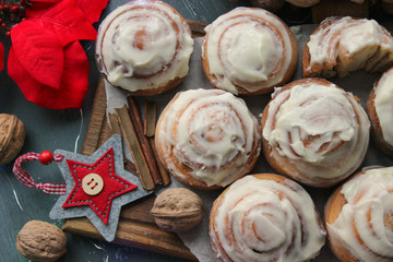 Cinnamon rolls for Christmas. Christmas cakes. Buns in glaze on a wooden table, scattered nuts and cinnamon sticks, rustic style. Homemade cake. Christmas background. Greeting card.