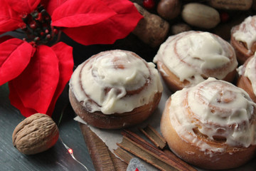 Cinnamon rolls for Christmas. Christmas cakes. Buns in glaze on a wooden table, scattered nuts and cinnamon sticks, rustic style. Homemade cake. Christmas background. Greeting card.