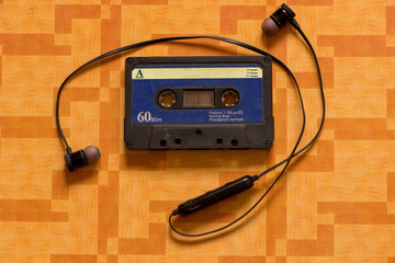 A cassette tape with headphones on an orange background