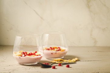 Homemade yogurt with pomegranate and flakes/two glass homemade yogurt with pomegranate and flakes on a white background with copy space, selective focus