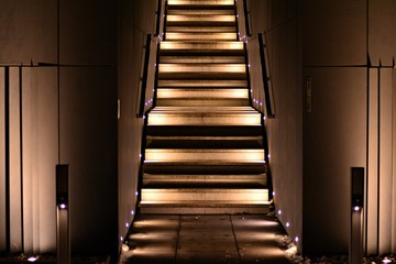 illuminated apartment building staircase exhaling up to entrance in night city