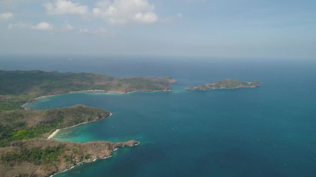 Aerial view of coast with tropical beach, island Limbones, lagoons and coral reefs. Neela cove, Philippines, Luzon. Coast ocean with turquoise water. Tropical landscape in Asia.