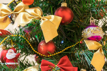 Christmas composition close-up, Christmas tree decorated with beautiful toys, colorful bows and Santa figures, glowing lights of garland