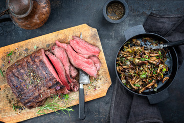 Traditional barbecue dry aged sliced roast beef steak with fried pioppino as top view on an old...