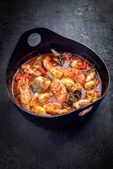 Traditional French Corsican fish stew with prawns, mussels and fish as top view in a modern design Japanese cast-iron roasting dish