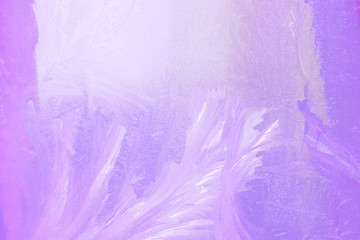 Fototapeta premium frosty pattern on the window draws winter purple color light from the window