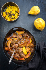 Traditional Iranian khoresh beh stew with chunks of lamb, quinces and saffron rice as top view in a modern style Japanese cast-iron roasting dish