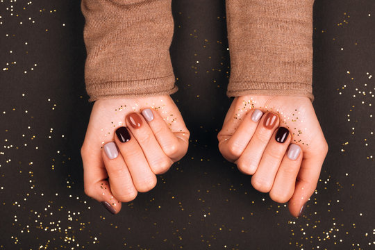 Holiday beautiful manicure with golden decorations. Dark tone.