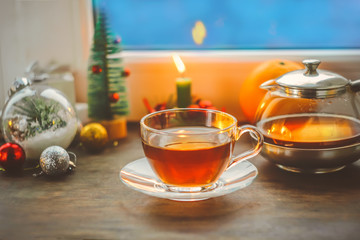 festive tea party. a cup of tea and a teapot. on the background of New Year and Christmas decorations. near the window with a blue, cold, winter background.