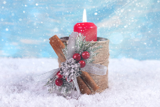 Candlestick with a candle against a background of falling snow